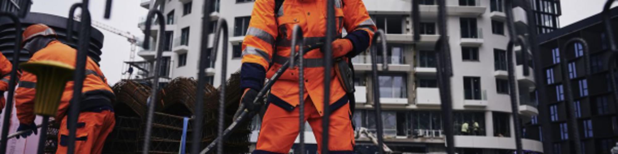 Construction worker on a construction site compacting concrete with a Wacker Neuson internal vibrator.