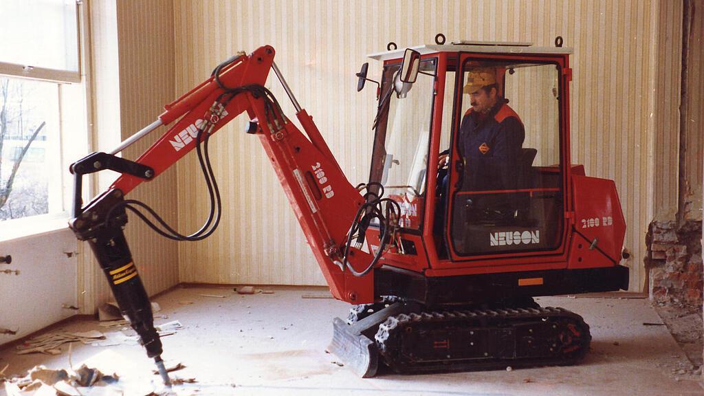 Première mini-pelle hydraulique Neuson en utilisation.